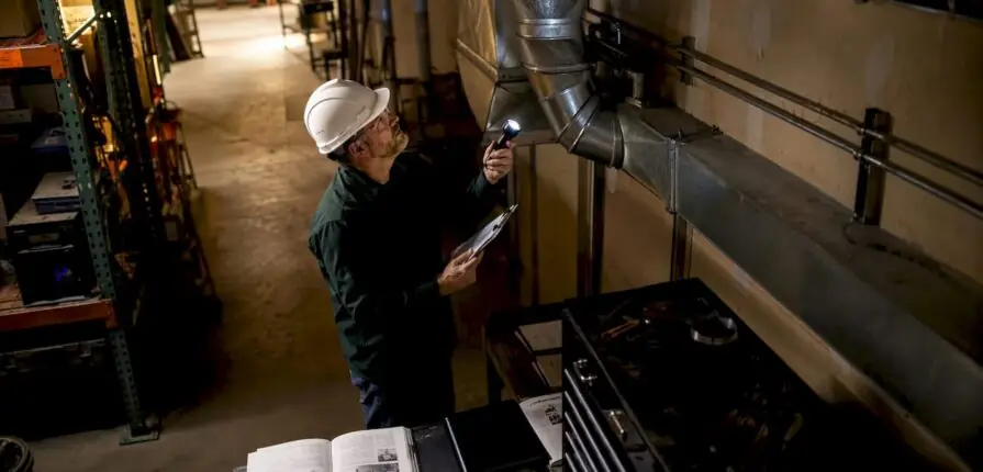 Technician inspecting warehouse ventilation ducts