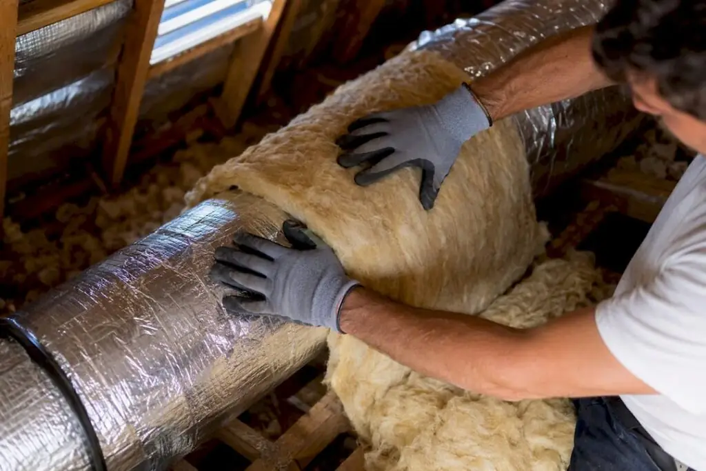 Technician hands wrapping duct insulation