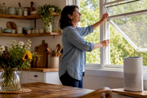 Woman adjusting curtains to improve home air quality