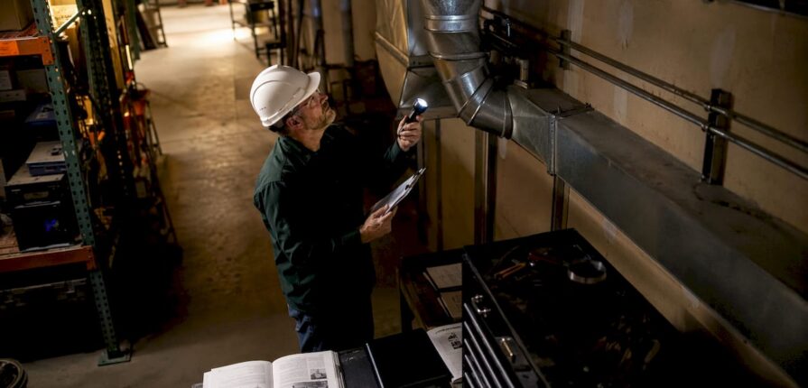 Technician inspecting warehouse ventilation ducts