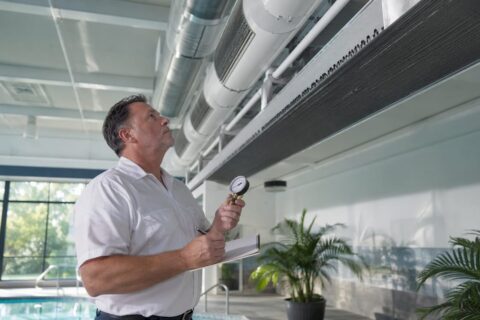 Technician inspecting indoor pool HVAC system
