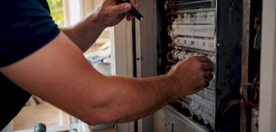 Technician inspecting frozen AC coil close-up