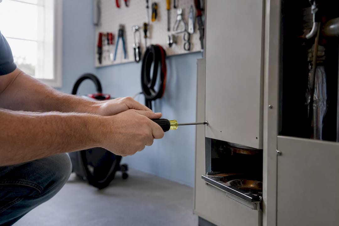 Hands opening HVAC panel with screwdriver