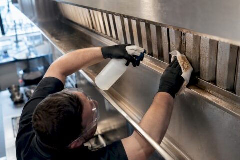 Technician cleaning commercial kitchen exhaust hood filter