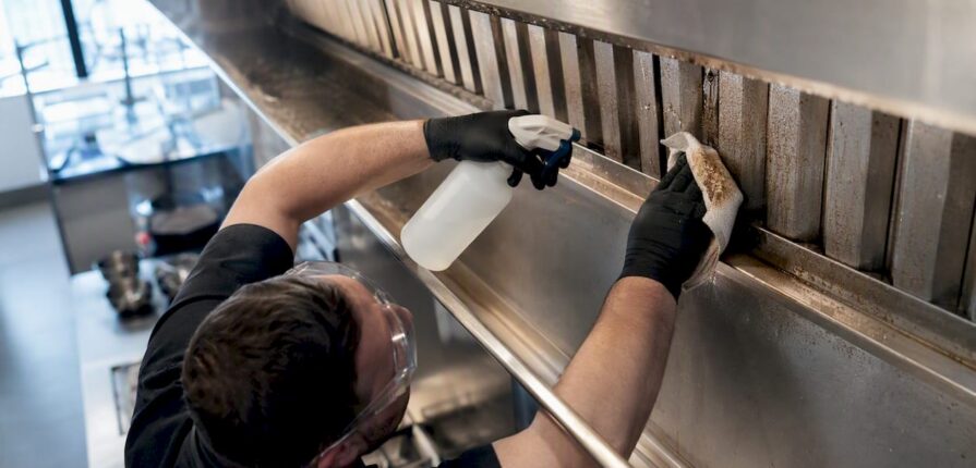 Technician cleaning commercial kitchen exhaust hood filter