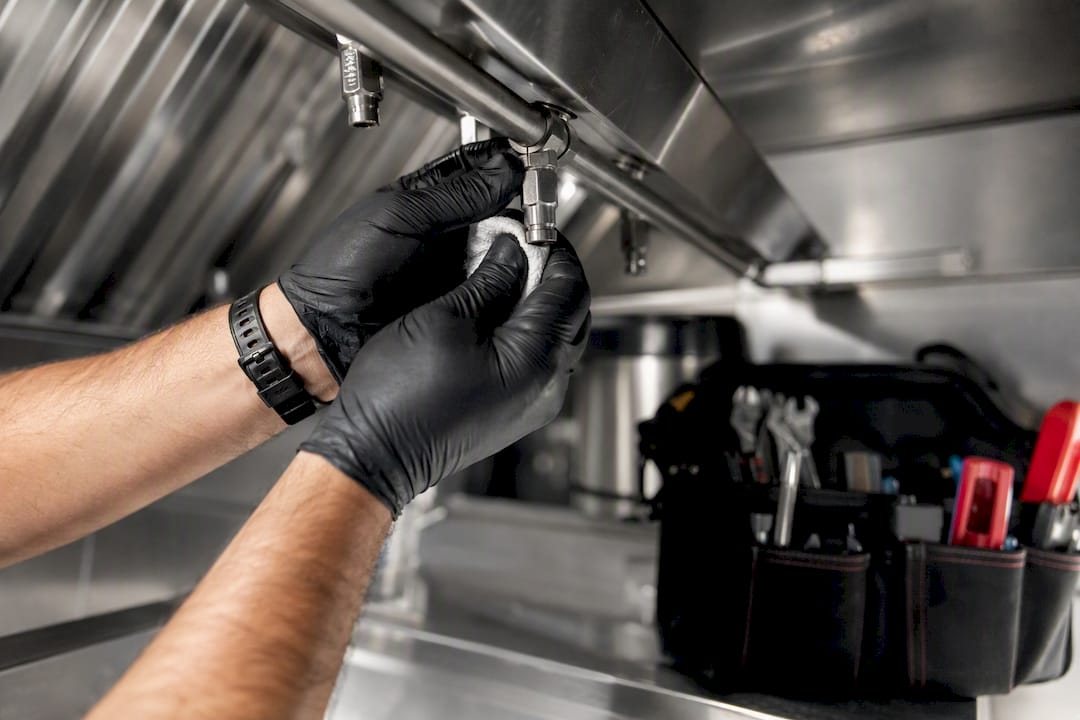 Technician inspecting kitchen hood fire suppression nozzle